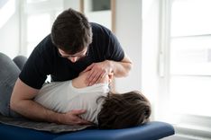 Ein Therapeut behandelt den Rücken einer Patientin.